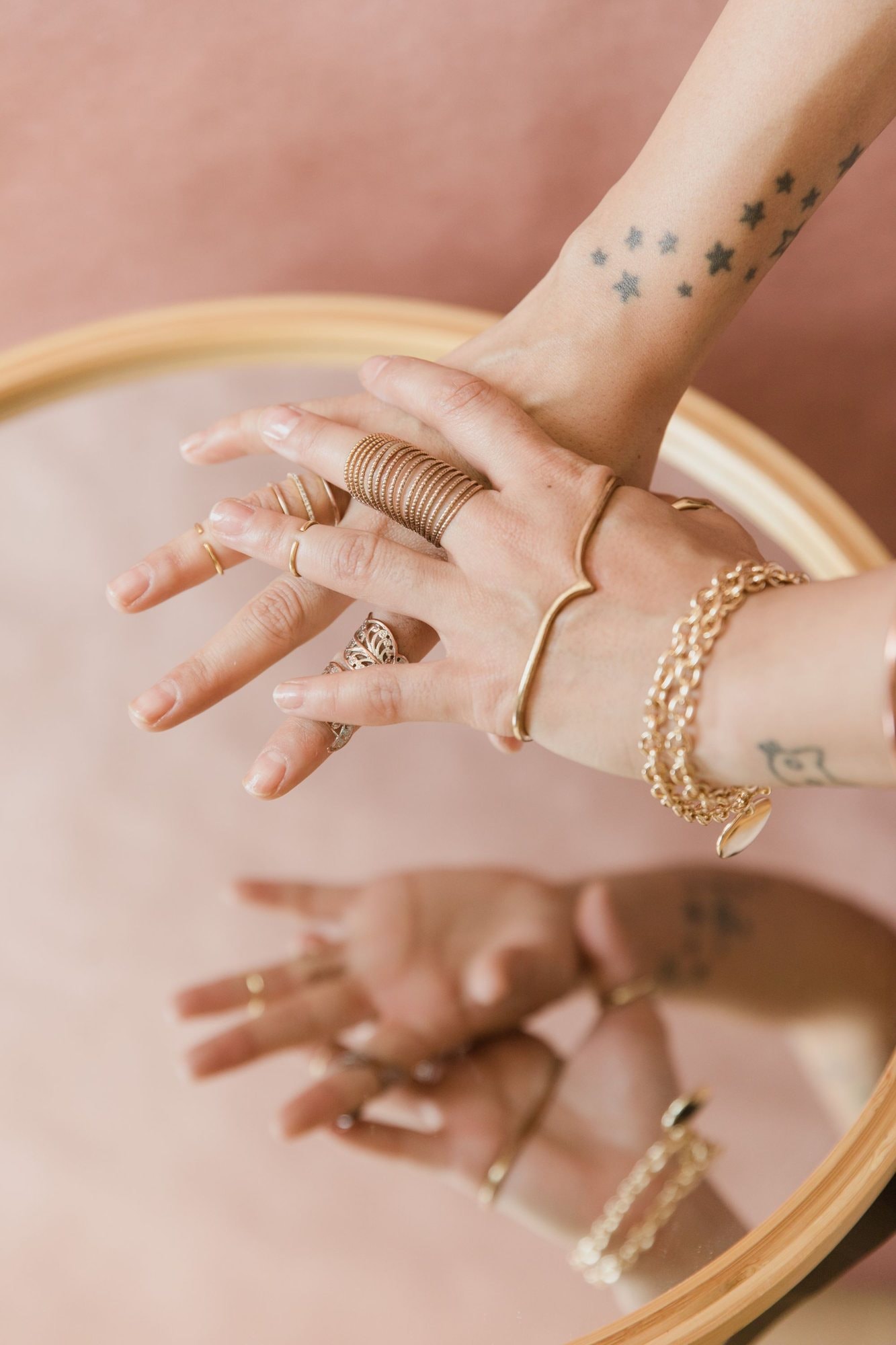 Mani con anelli e bracciali d’oro riflesse in uno specchio