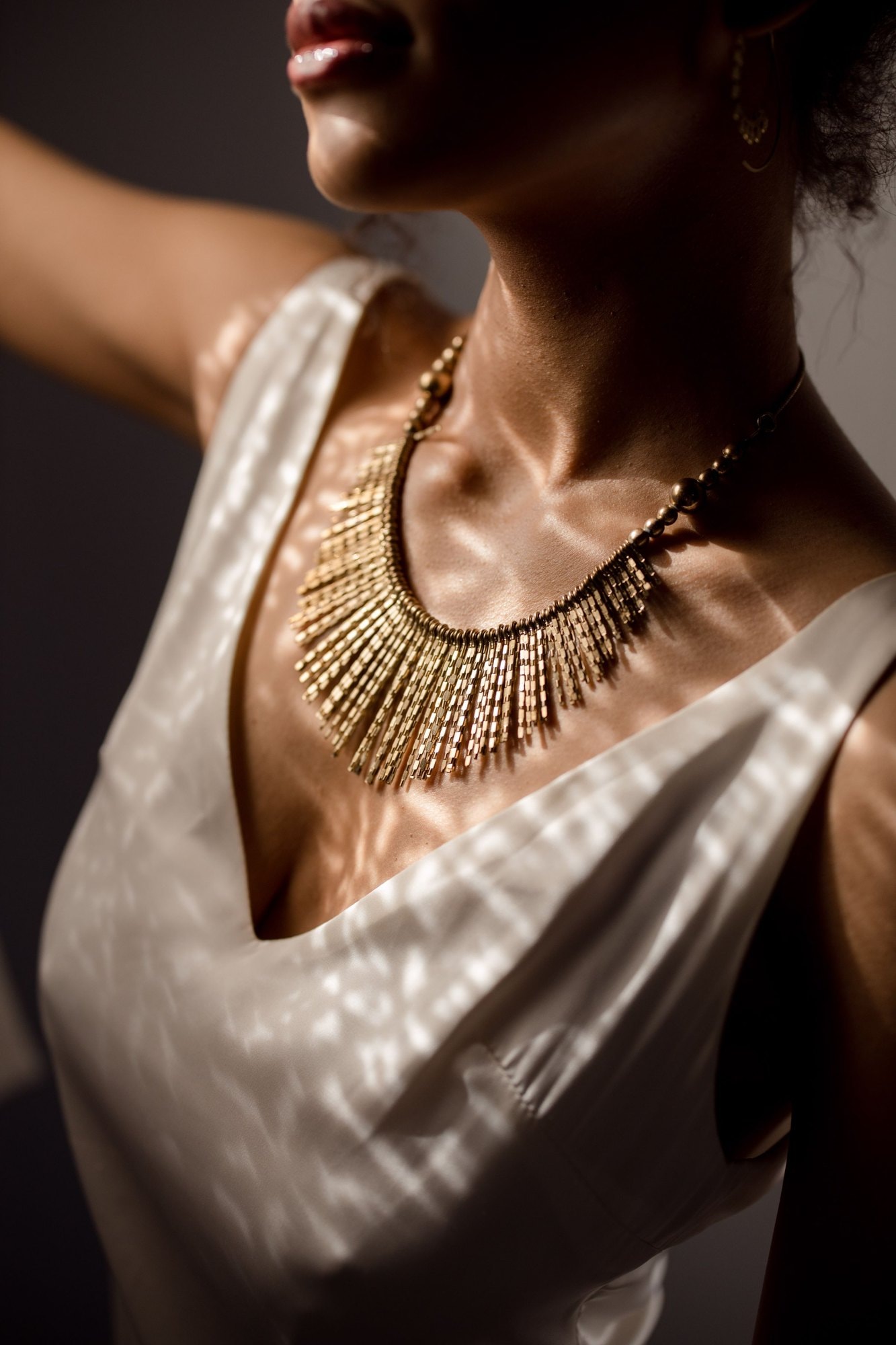 Una collana d’oro a frange su un abito di raso chiaro