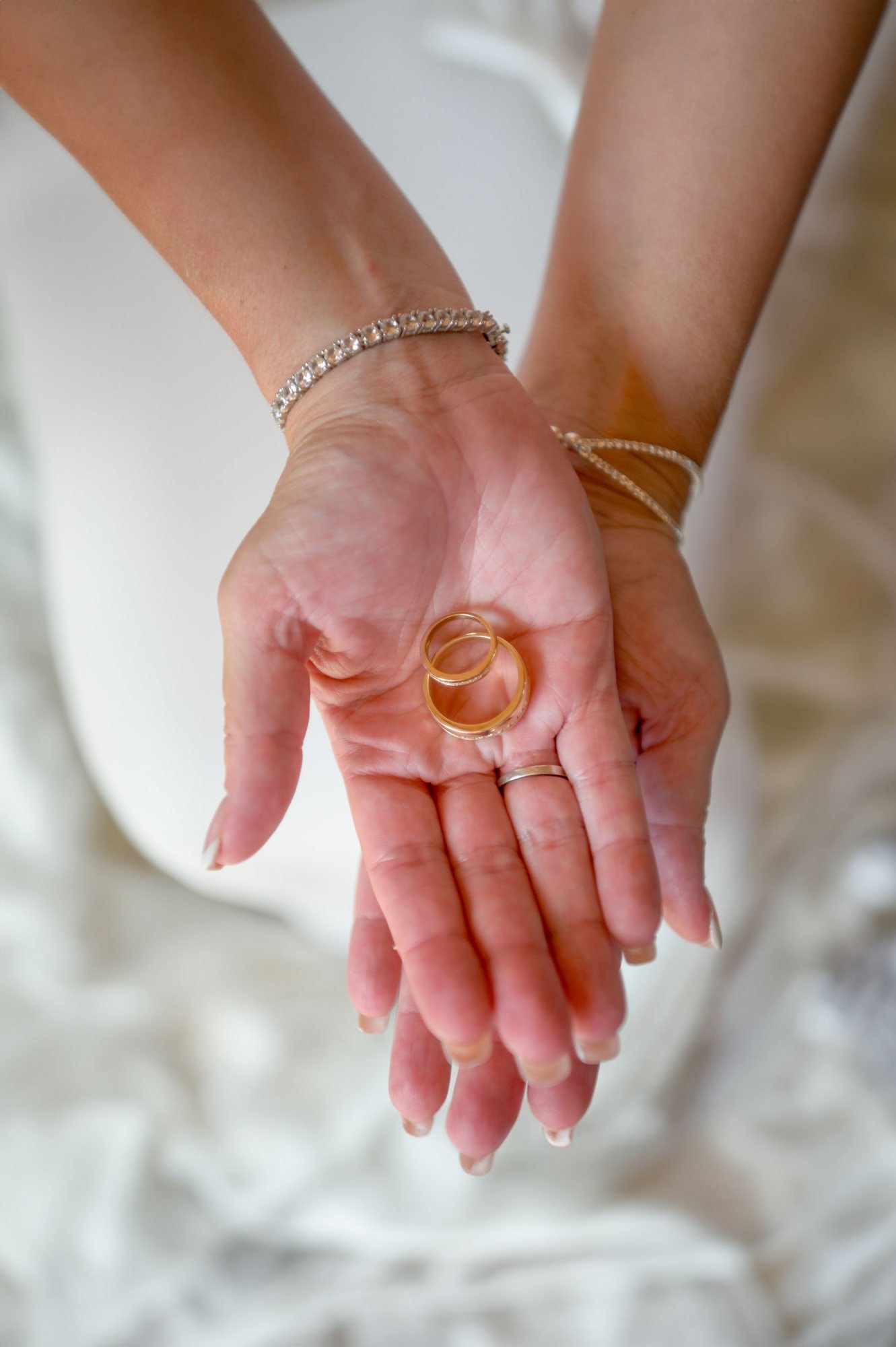 Mani con bracciali sottili e anelli d’oro nel palmo