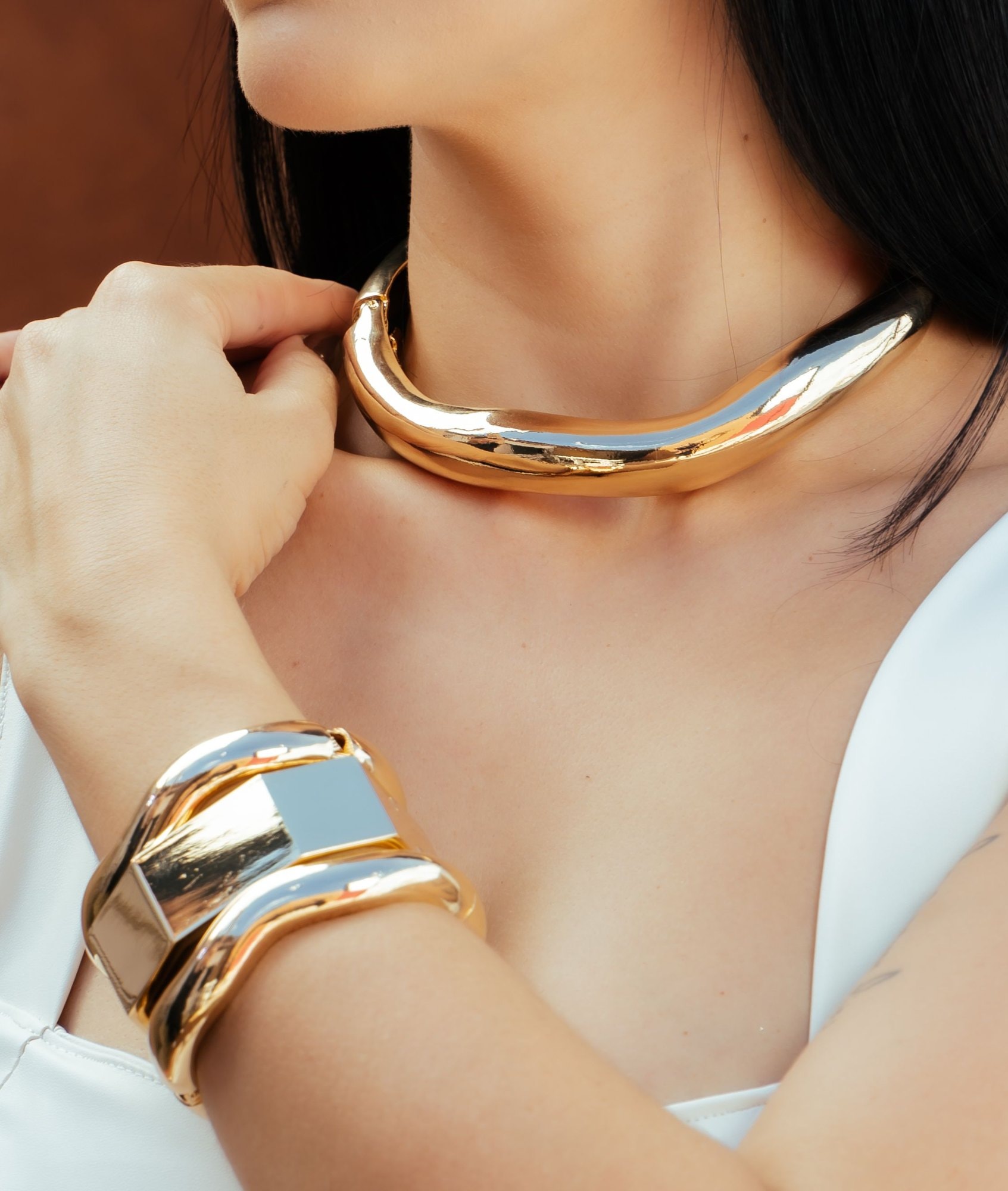 Un girocollo rigido e un bracciale d’oro indossati
